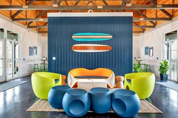 a lounge area with blue chairs and a blue wall with a surfboard